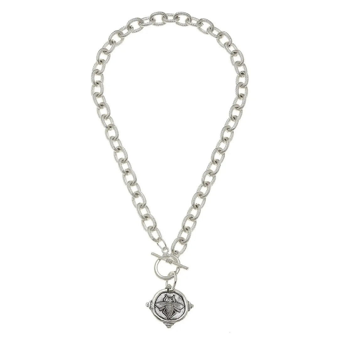 A silver-toned chain bracelet with a toggle clasp and a round compass pendant featuring an engraved bee design, shown on a plain white background.