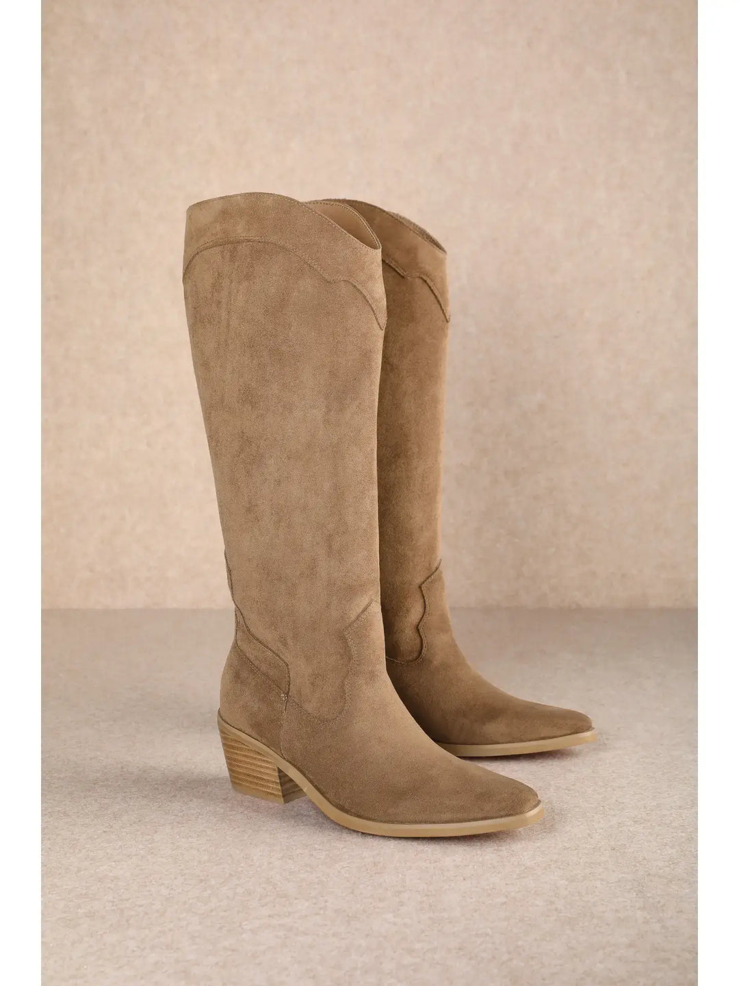 Pair of brown knee-high boots on a beige background